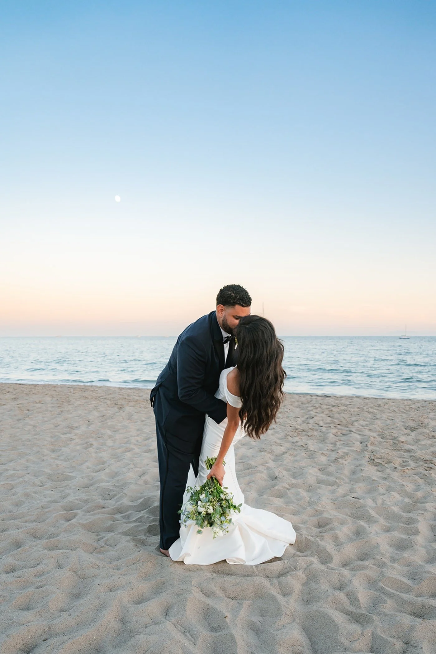Bride and groom kiss on beach at Cabrillo Pavilion