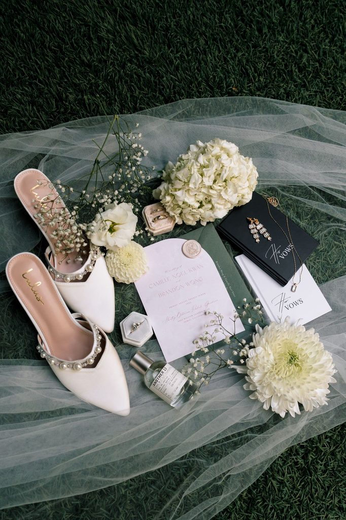 Bridal shoes, invitation suite and white blooms laid on tulle, Hartley Botanica wedding details