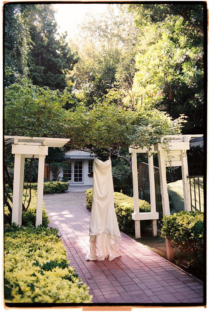 Wedding dress hanging on the white pergola at Hartley Botanica, photographed on film