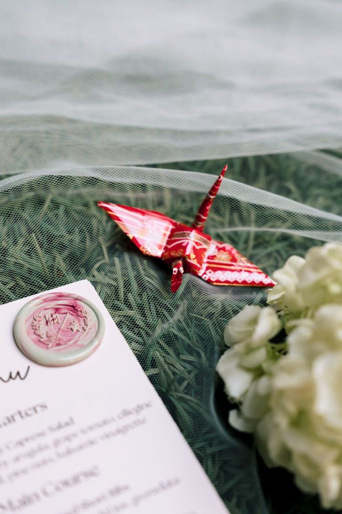 Menu card with a red origami crane resting on tulle