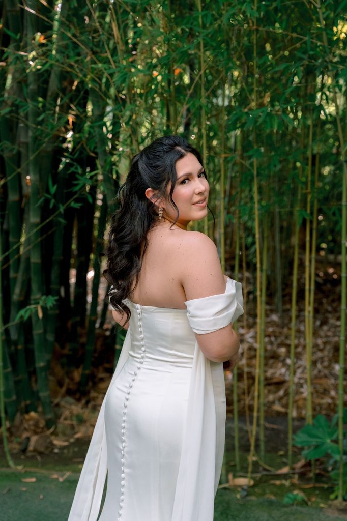 Bride looking over her shoulder in an off-the-shoulder satin gown