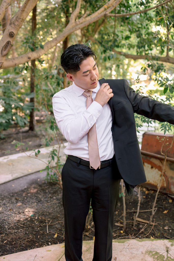 Groom buttoning his shirt cuff in the garden before the ceremony