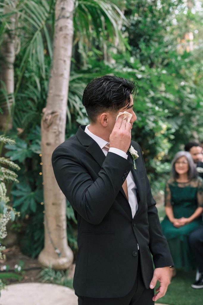 Groom wiping away a tear as the bride walks in