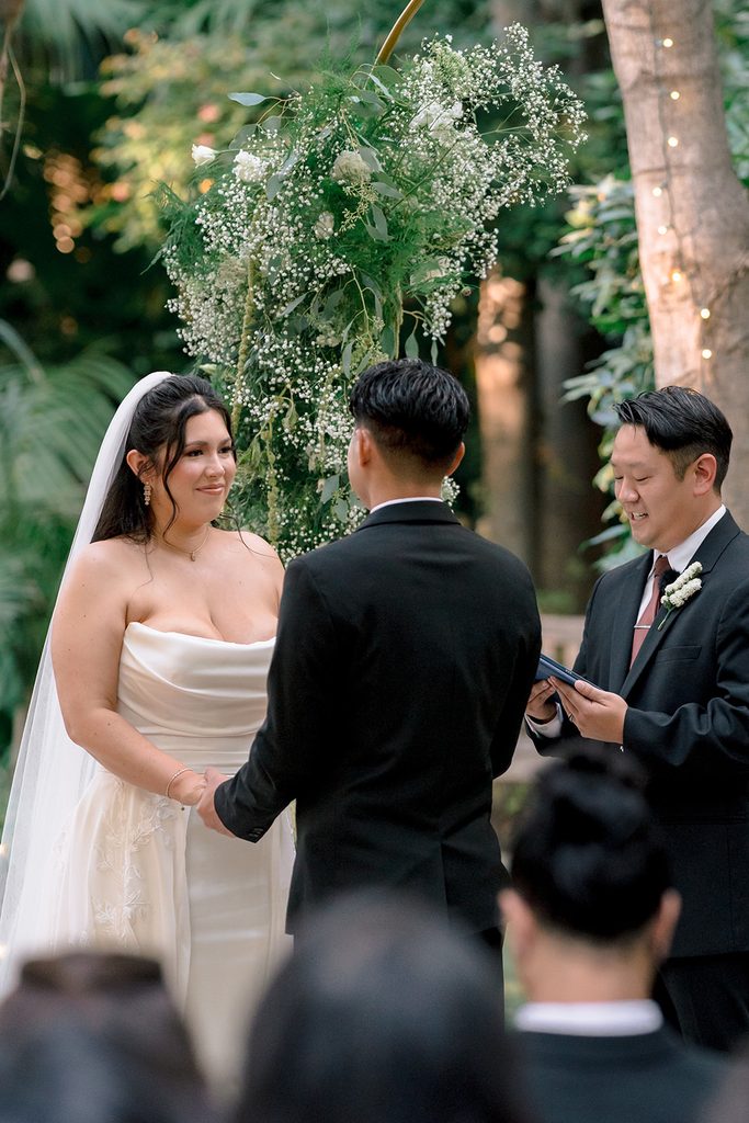 Bride and groom holding hands during the ceremony at Hartley Botanica