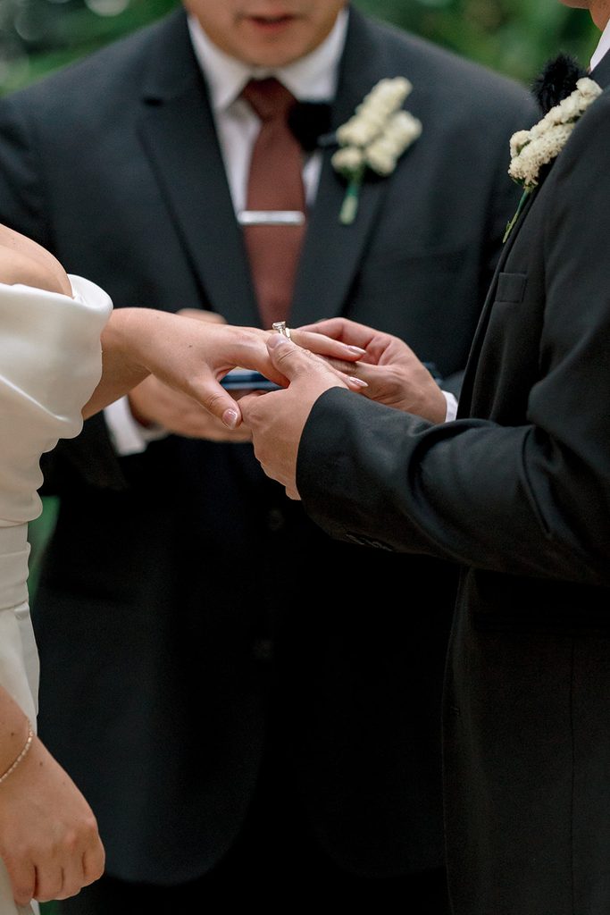 Groom placing the wedding ring on the bride's finger, close up