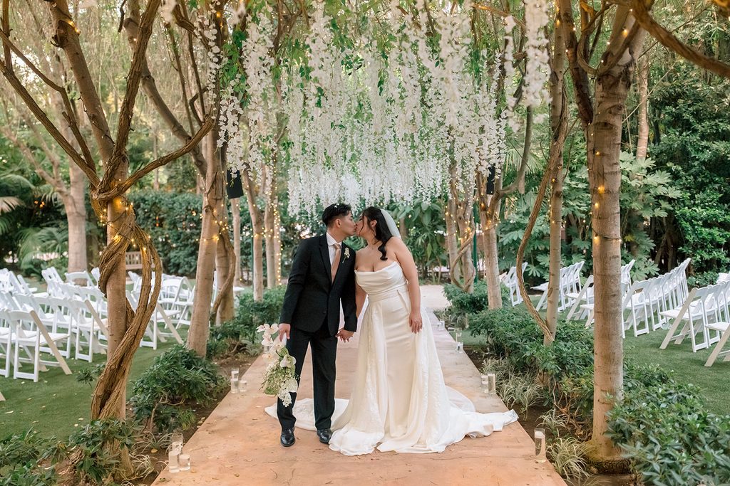 Newlyweds walking the tree-lined ceremony aisle at Hartley Botanica in Somis