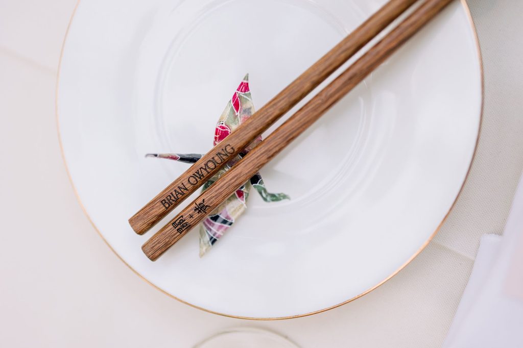 Wooden chopsticks and an origami crane on a white place setting
