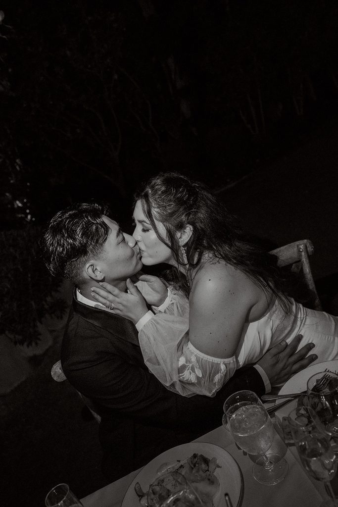 Bride and groom kiss at the reception, black and white