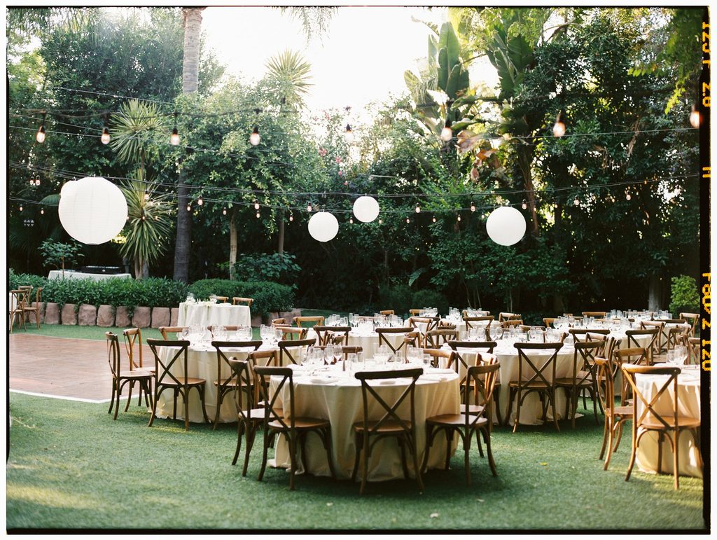 Reception tables beneath paper lanterns in the garden at Hartley Botanica